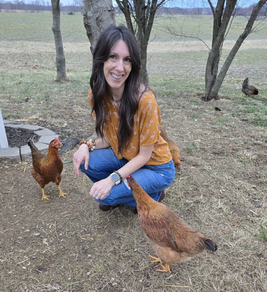 Photo of Dana sitting with her chickens